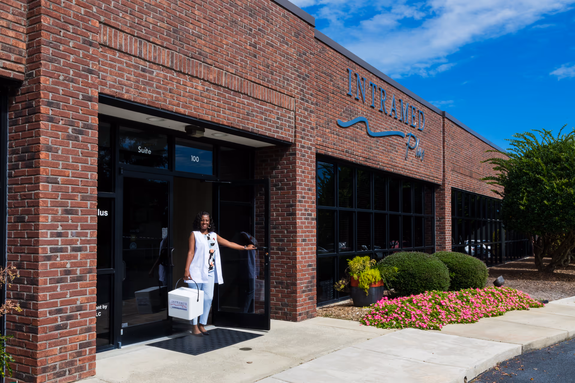 A woman stands at the entrance of a brick senior living facility named Intramed Plus.