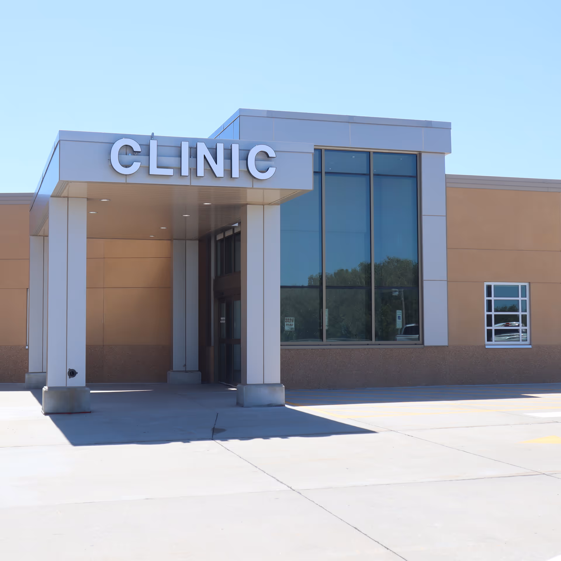 Modern clinic entrance with glass windows and a covered driveway.