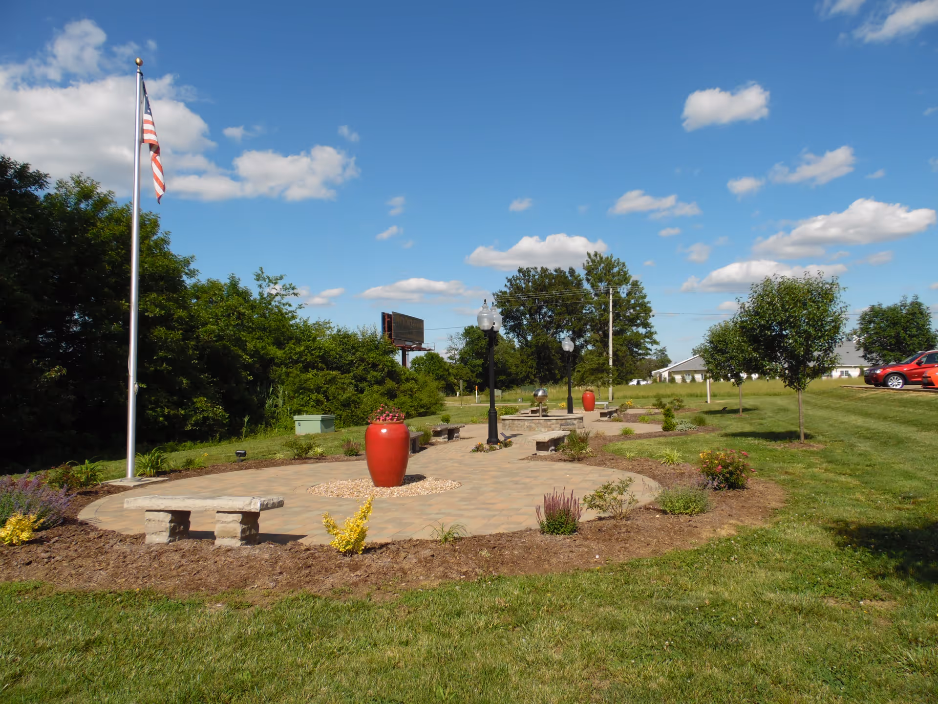 Outdoor courtyard at Hospice of Southern Illinois Marion Location with benches, lamp posts, and red planters.