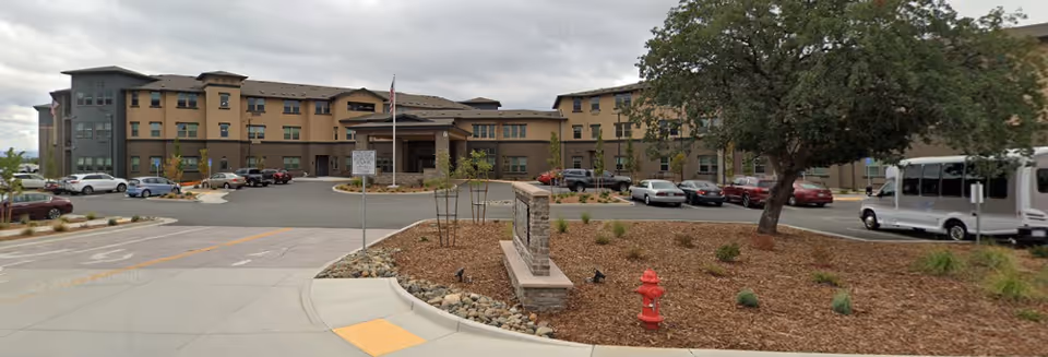 Exterior view of Hilltop Springs Senior Living front entrance with parked cars.
