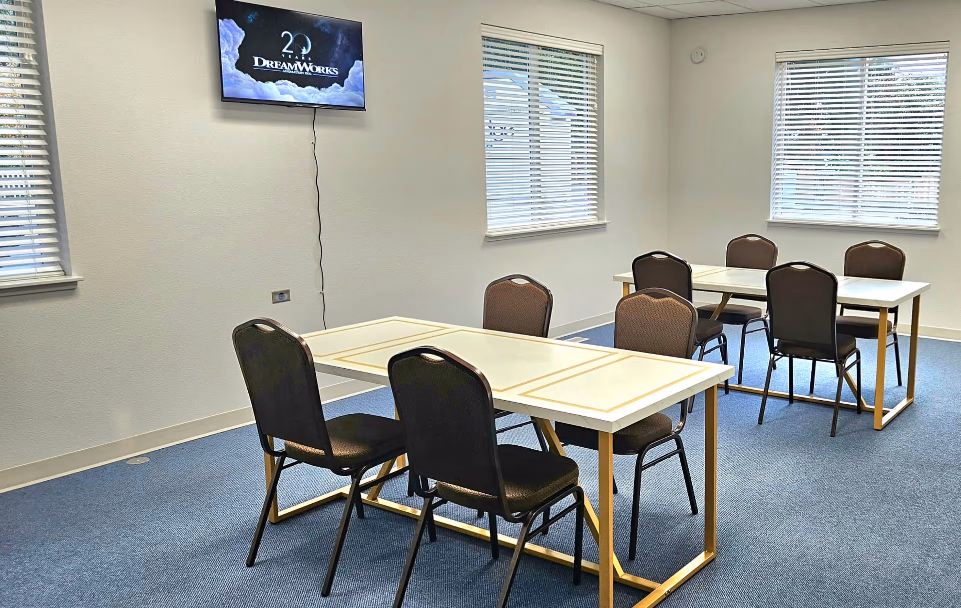 Interior dining area with two tables, chairs, and windows with blinds.