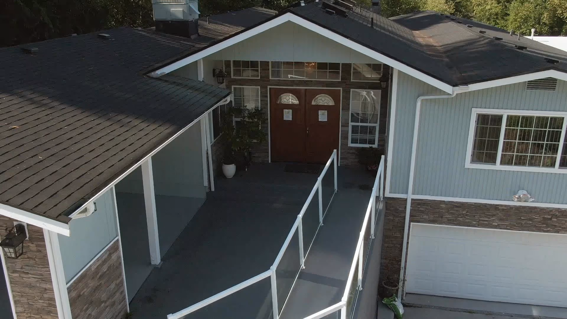 Front exterior of a light-blue residential building with a ramp leading to double entry doors and an attached garage.