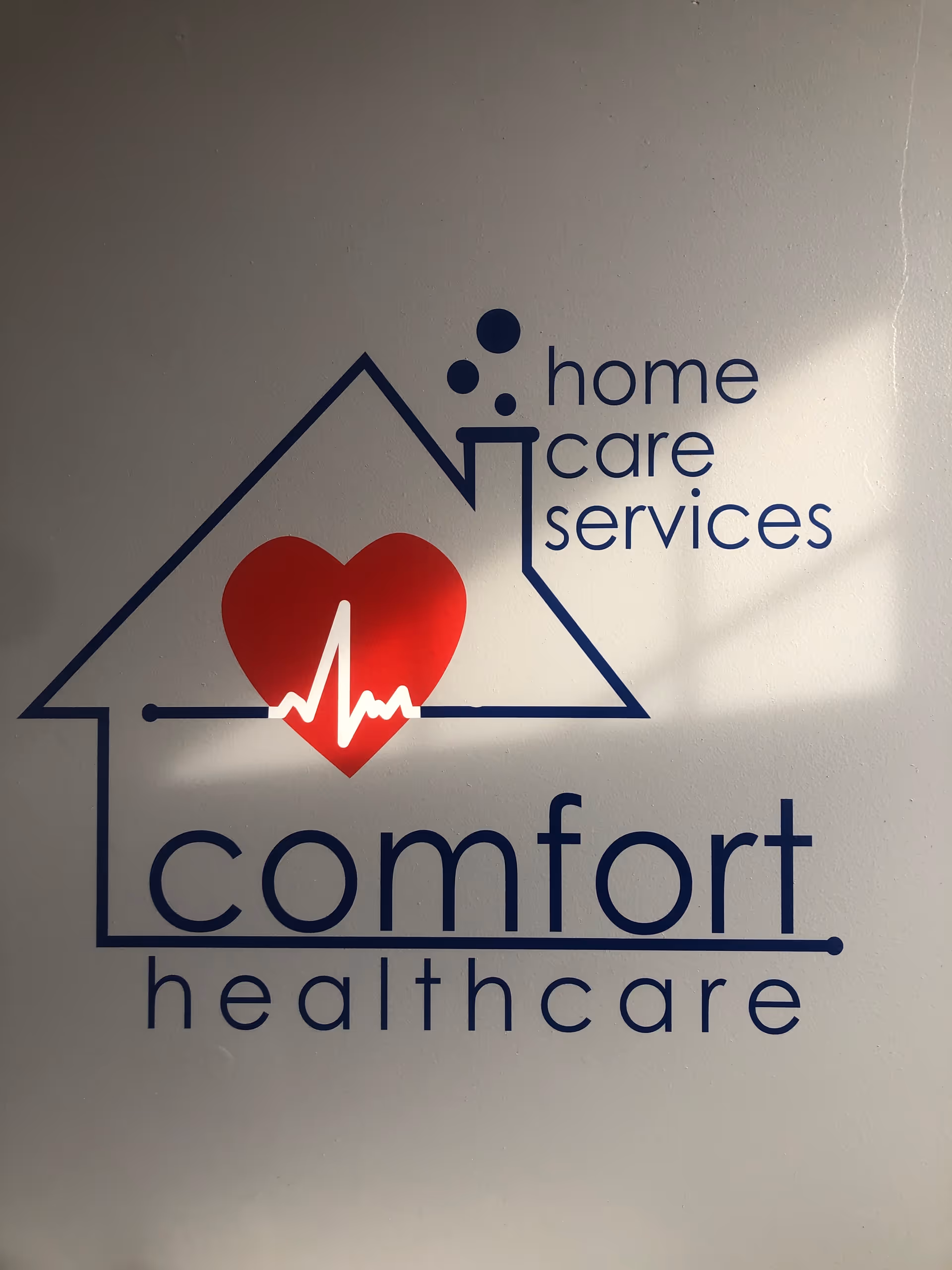 A wall sign displays a blue, red heart logo reading Comfort Healthcare and Home Care Services.