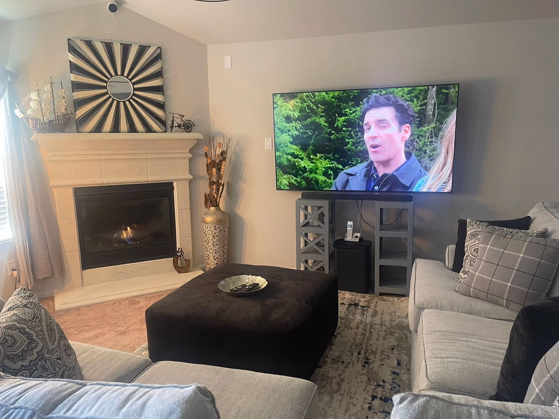 Cozy living room with a fireplace, large TV, and gray sectional seating.
