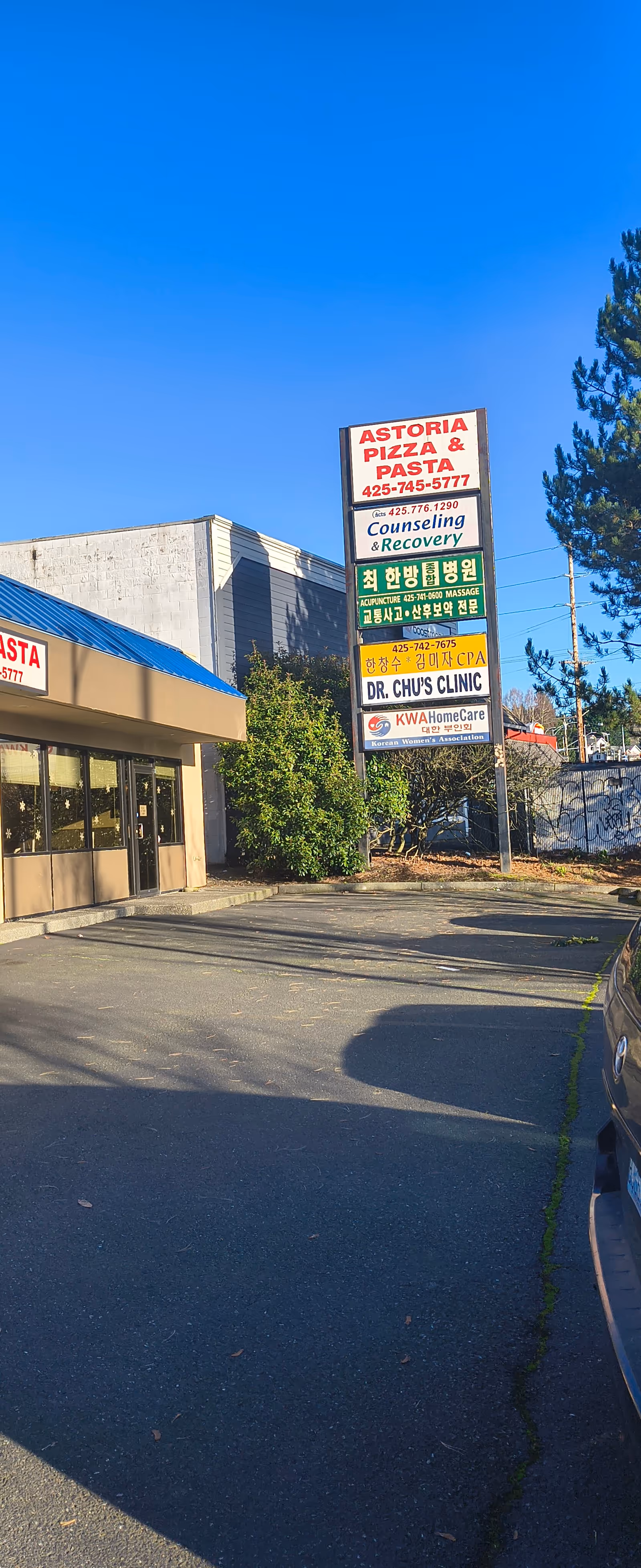Exterior storefront with a tall multi-sign board advertising KWA HomeCare and other businesses