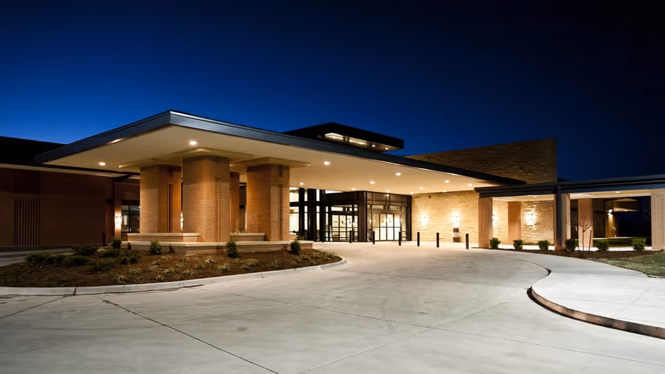 Night exterior of a modern senior living facility entrance with brick columns.