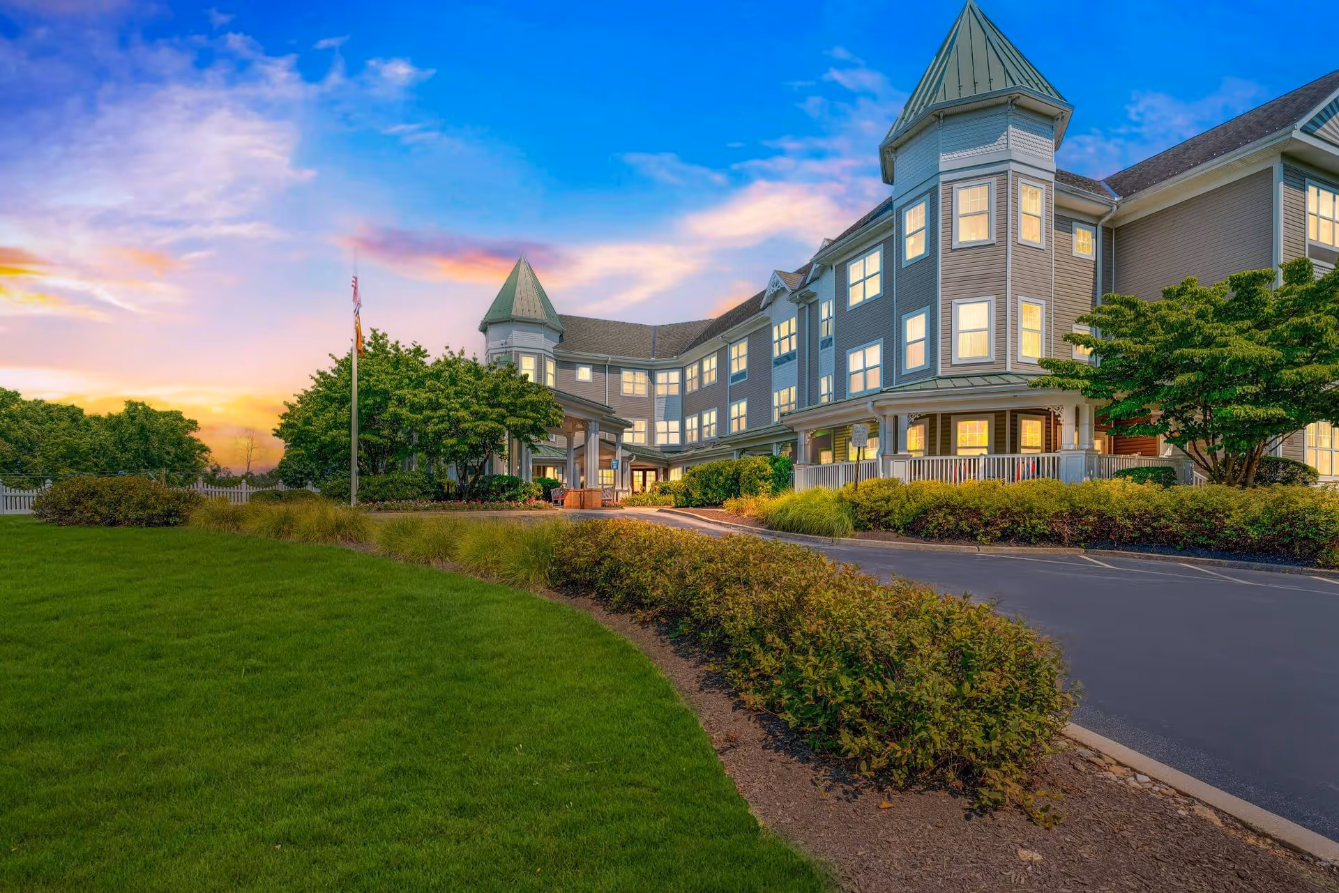 Sunrise of Paoli exterior building with blue siding, towers, and manicured lawn.