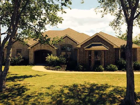 Front exterior of a brick Lakewest Assisted Living facility with a manicured lawn and trees.