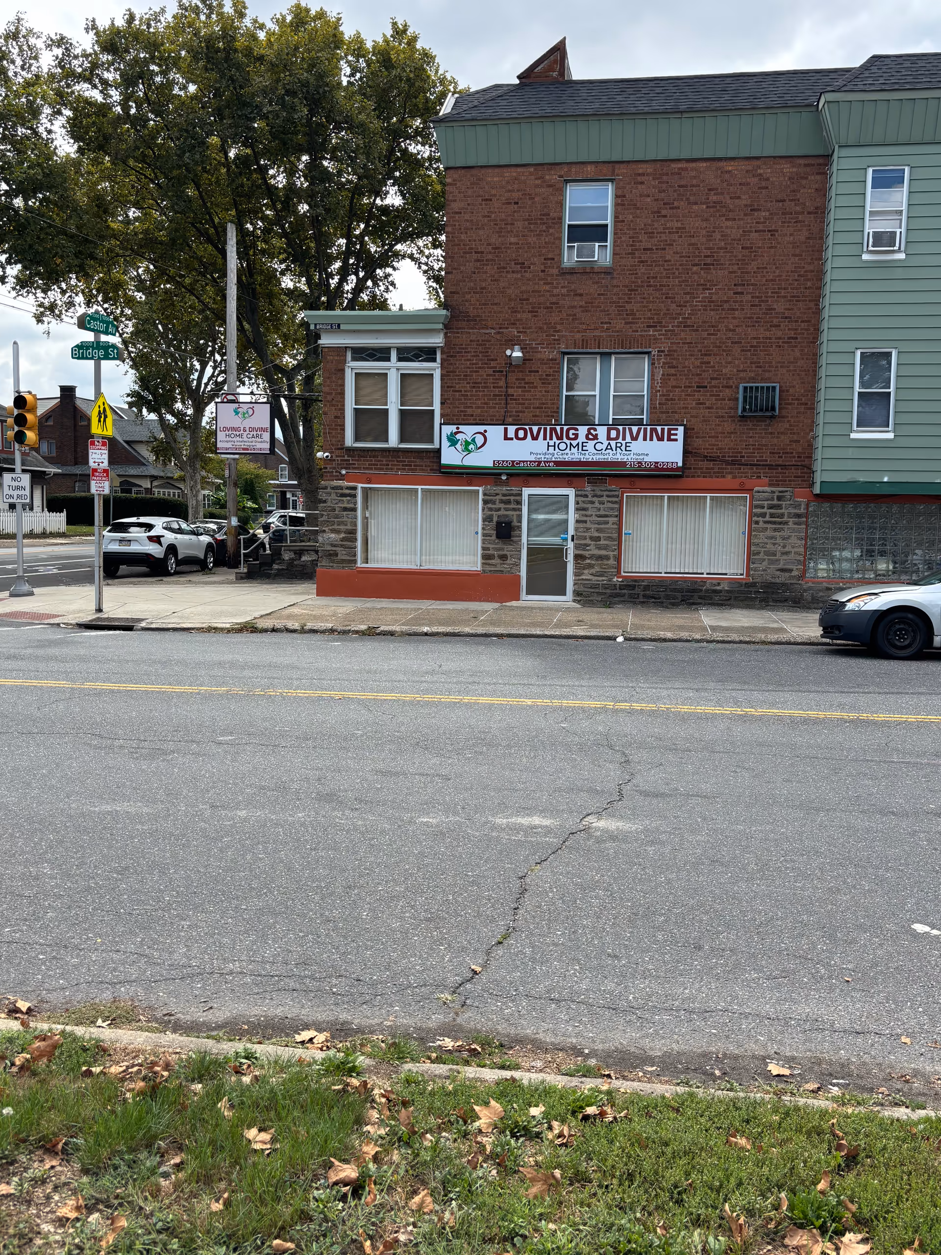 Two-story brick building with Loving and Divine Home Care sign on storefront along a street.