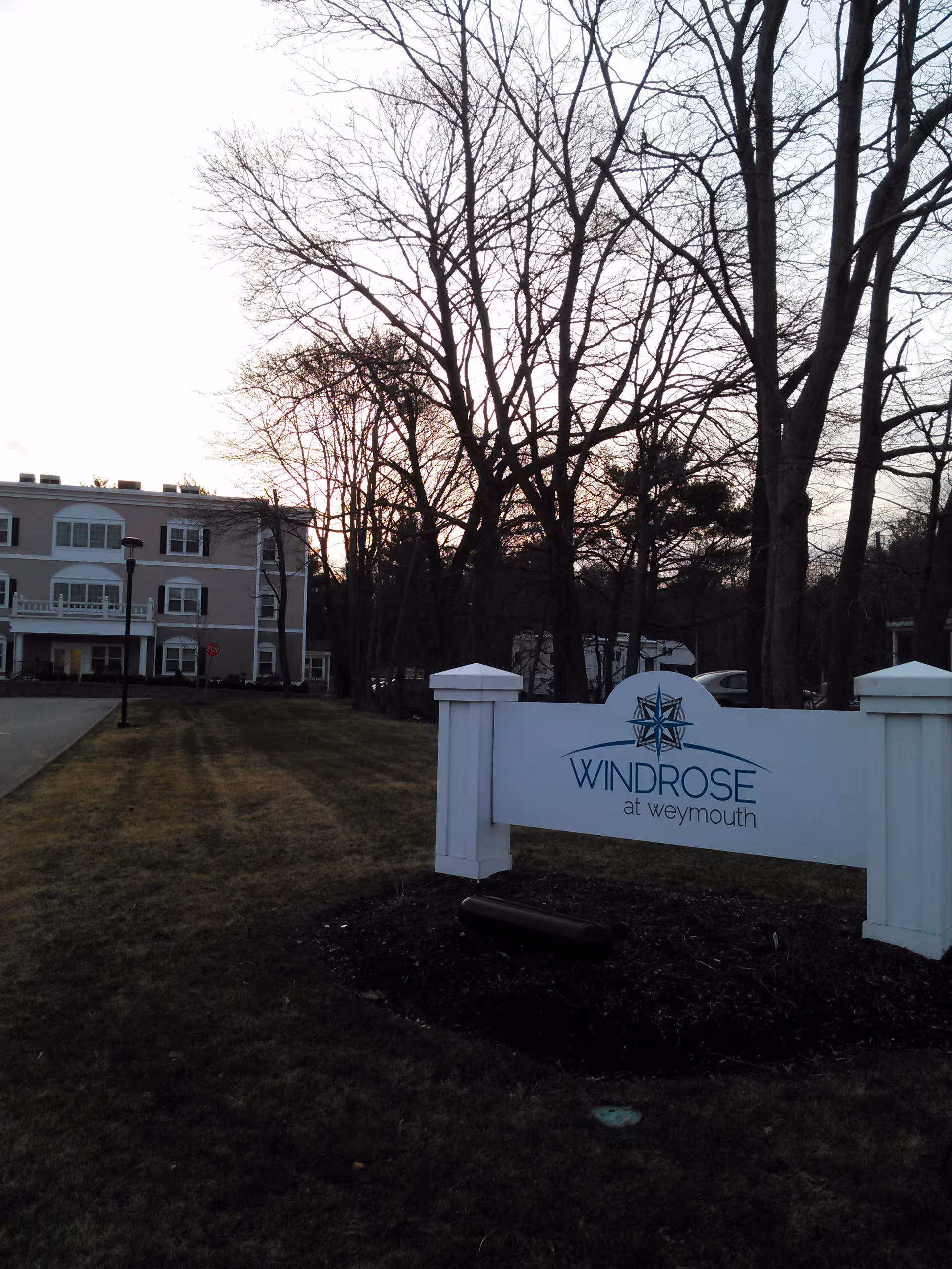 Exterior view of Windrose at Weymouth sign with a residential building and trees.