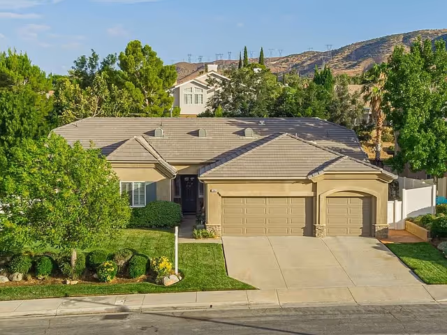 Exterior view of a tan, single-story building with a two-car garage and green landscaping