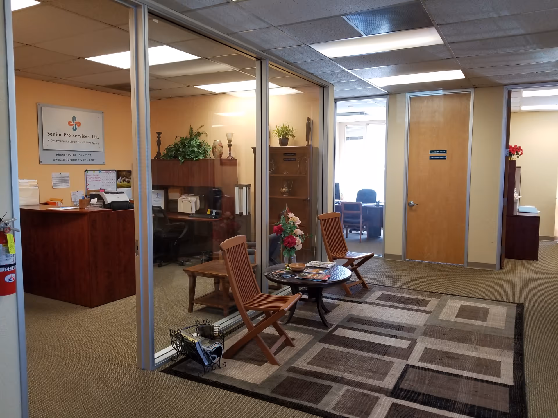 An office lobby with glass-walled rooms, a reception desk, and seating area.