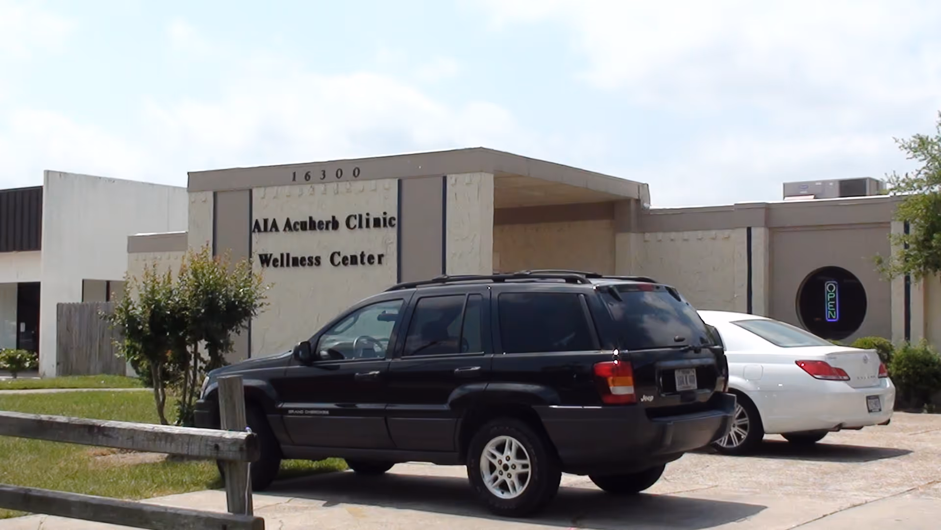 Exterior view of AIA Acuherb Clinic Wellness Center with parked cars.