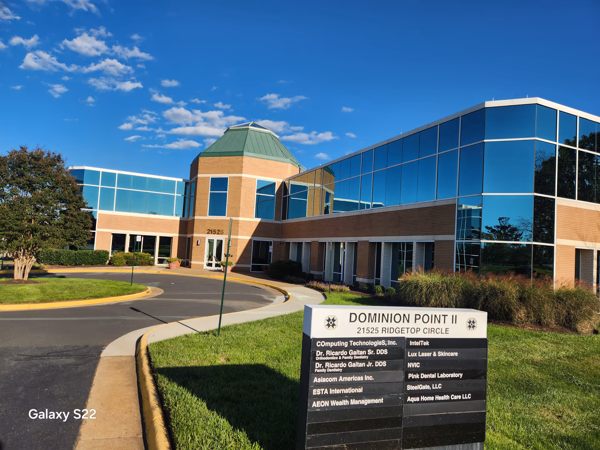 Exterior view of Aqua Home Health Care facility with brick and glass facade and landscaped lawn.