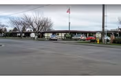 Single-story nursing home exterior with parked cars under a covered awning and flag.