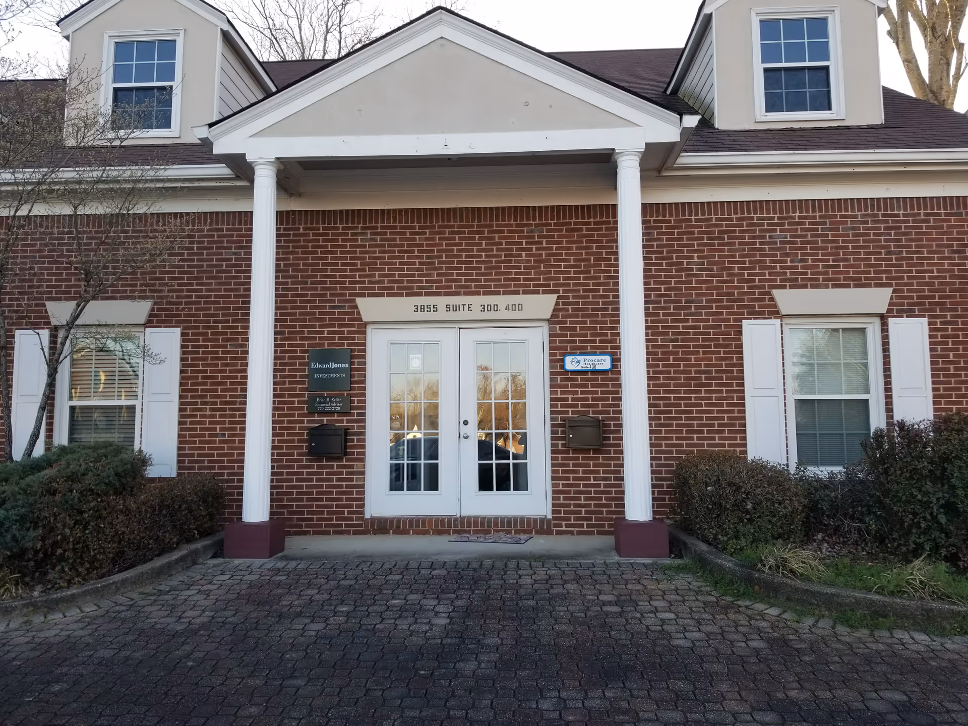 Brick senior living facility exterior with white columns and double glass doors at entrance.