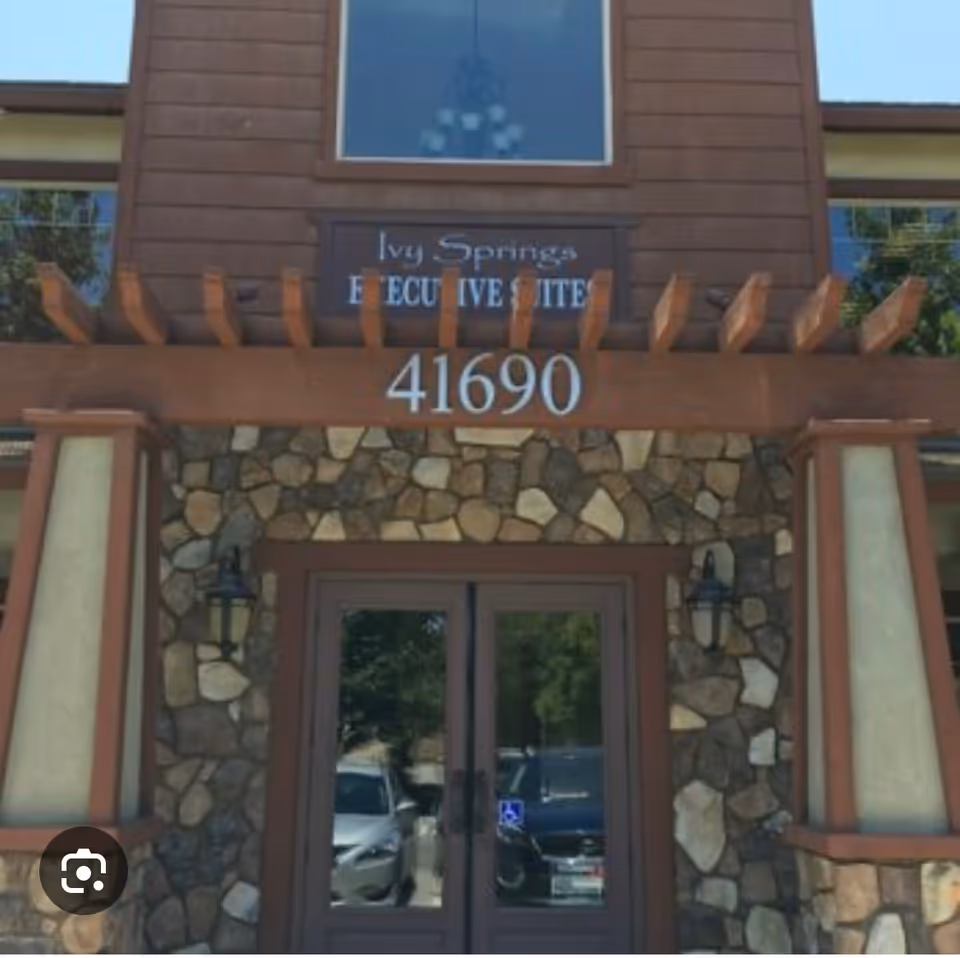 Front entrance of a stone-and-wood building with address 41690 and glass doors.