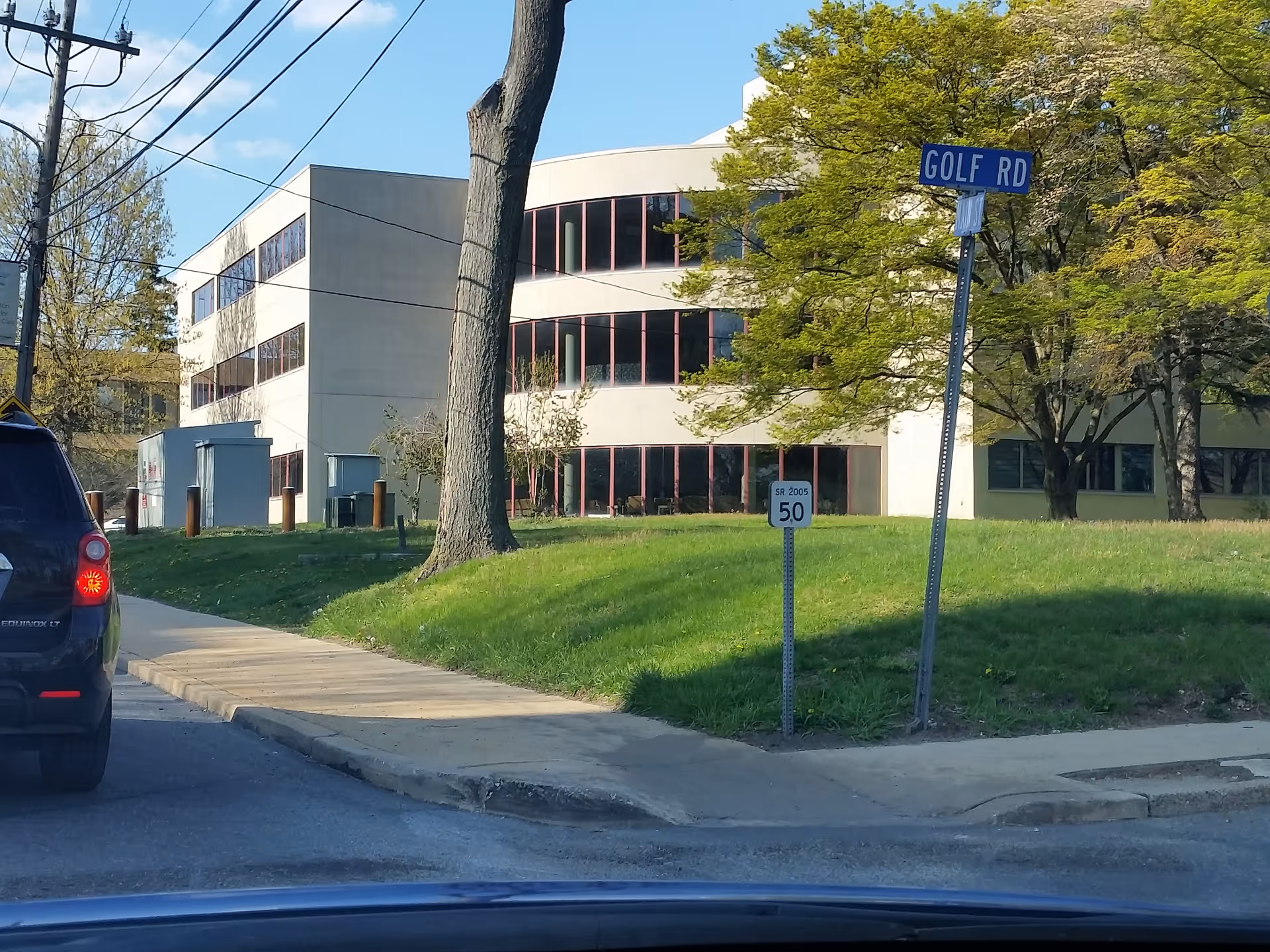 Exterior view of Mercy Home Health facility with curved glass facade and street signs.