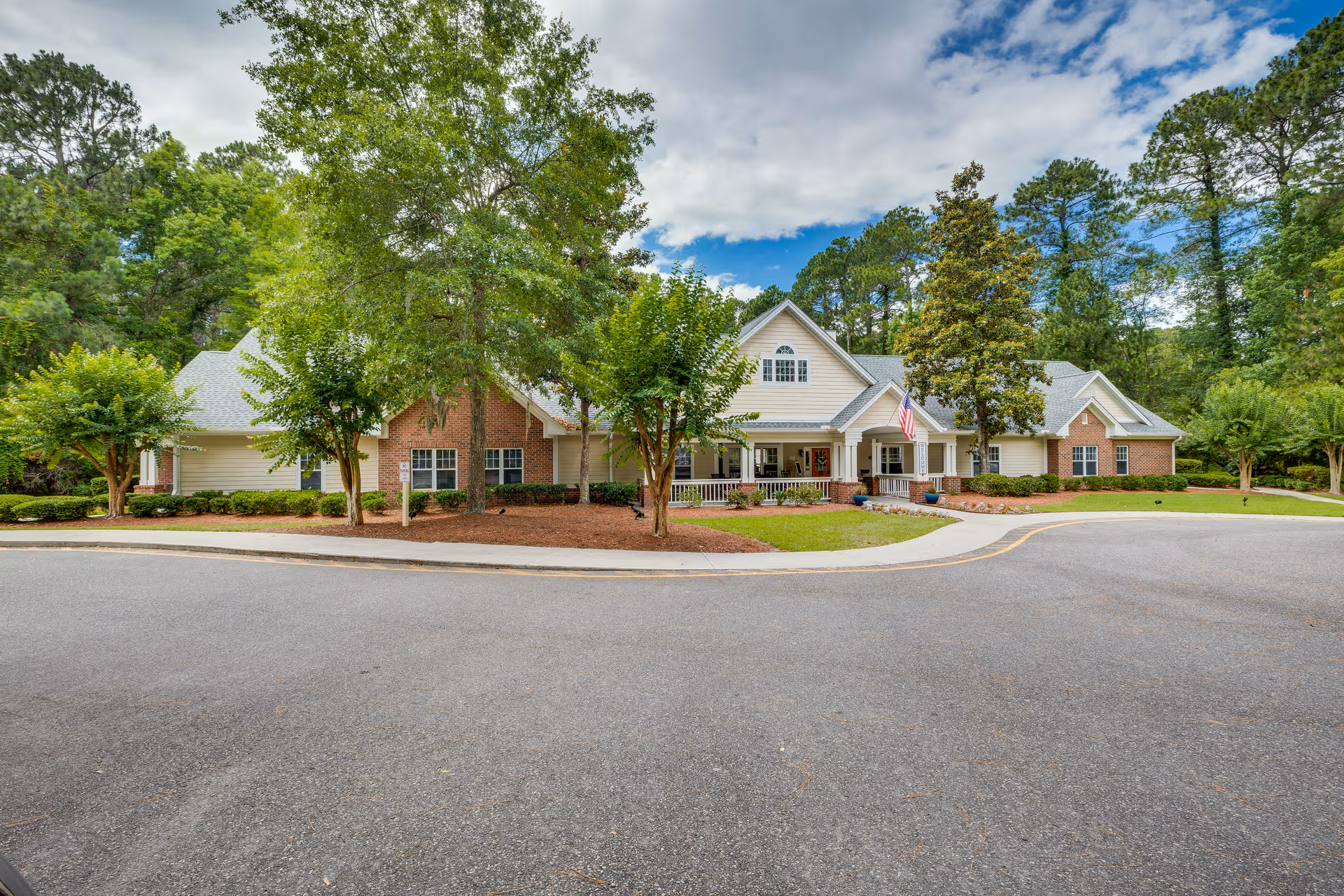 Front exterior view of Harbor Cove Memory Care building with trees, parking circle, and entrance.