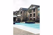 Outdoor pool area in front of a brick, multi-story senior living building.