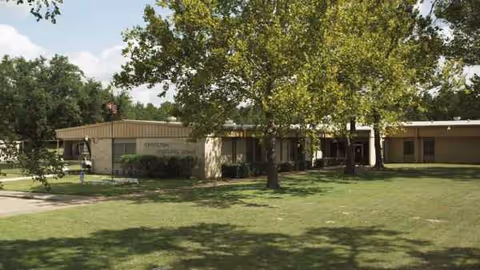 Groveton Nursing Home exterior with lawn, trees, and a low building facade.