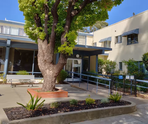 Exterior view of Bellaken Garden facility with entrance ramp and large tree in foreground.