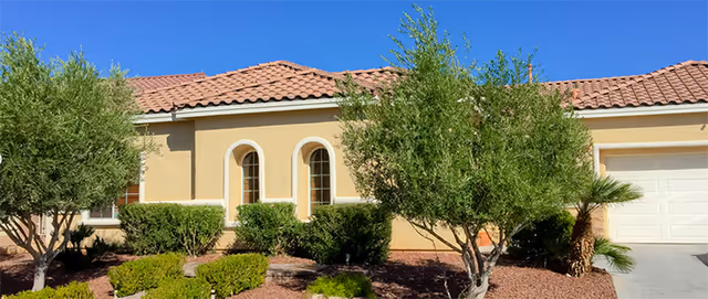 Front view of a tan, tile-roofed senior living facility with arched windows.