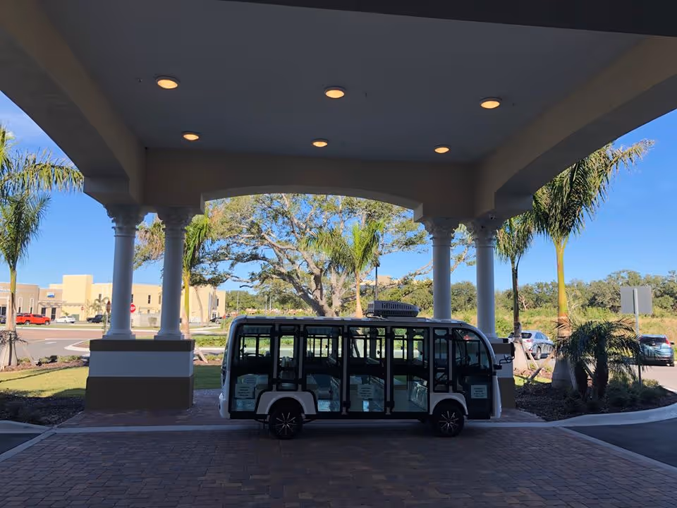 Shuttle van parked under a covered portico at a senior living facility entrance.