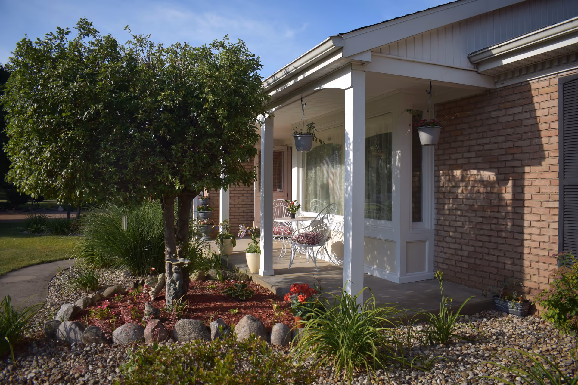 Front porch of EmbraceCare of Indiana, a brick senior living facility, with chairs and planters.