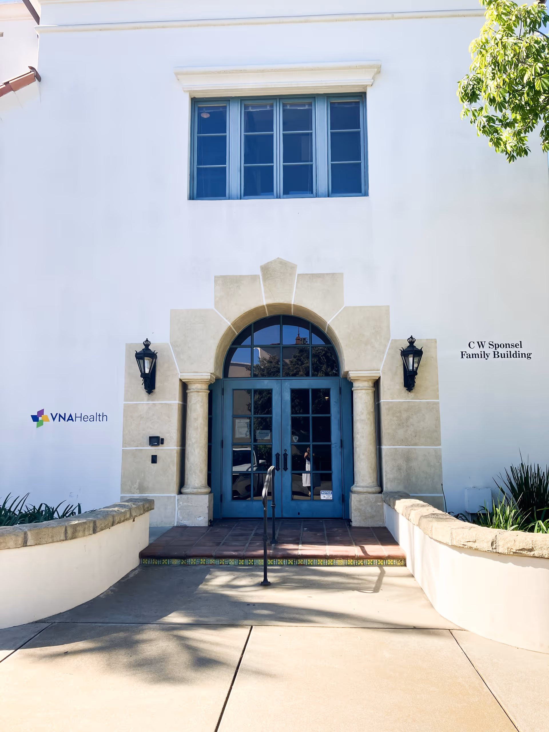 White exterior building with blue arched entrance and VNA Health logo.
