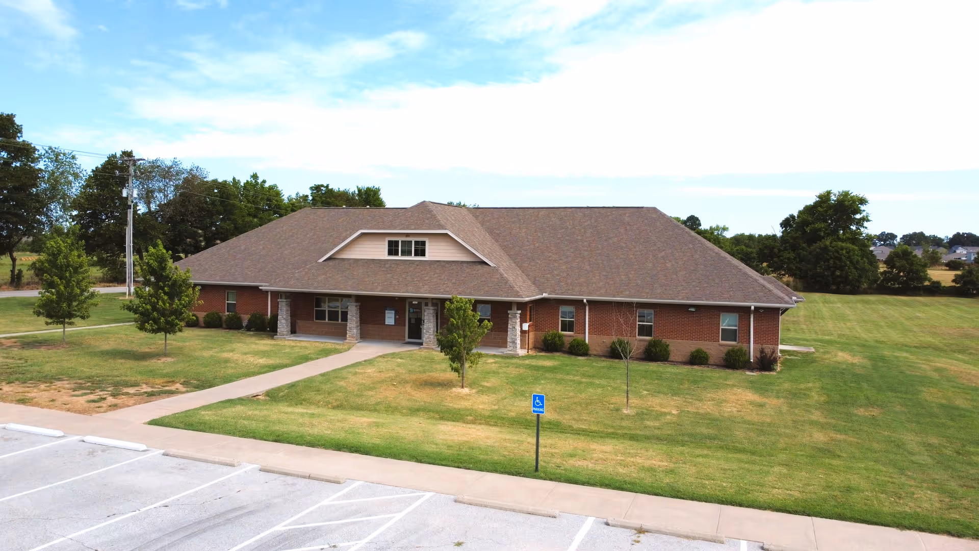 Single-story brick senior care building with a gabled roof and surrounding lawn.