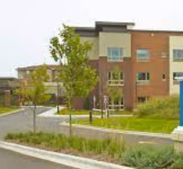 Exterior view of Monarch Landing facility with trees and landscaping along a sidewalk.