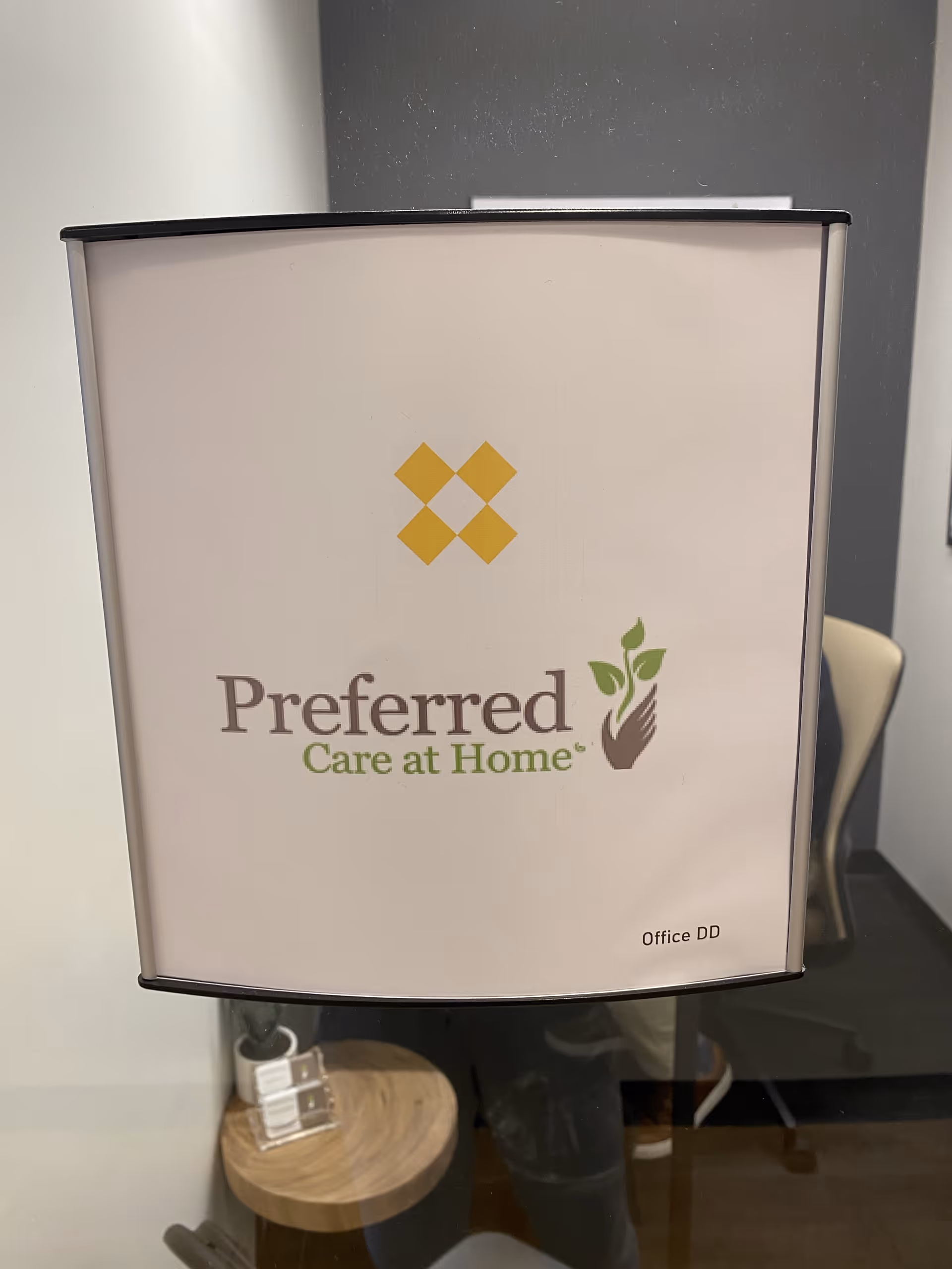 Close-up of a white sign featuring Preferred Care at Home logo indoors.