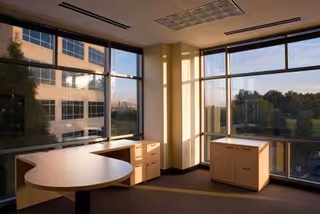 Bright interior room with large windows, a curved desk, and filing cabinets.