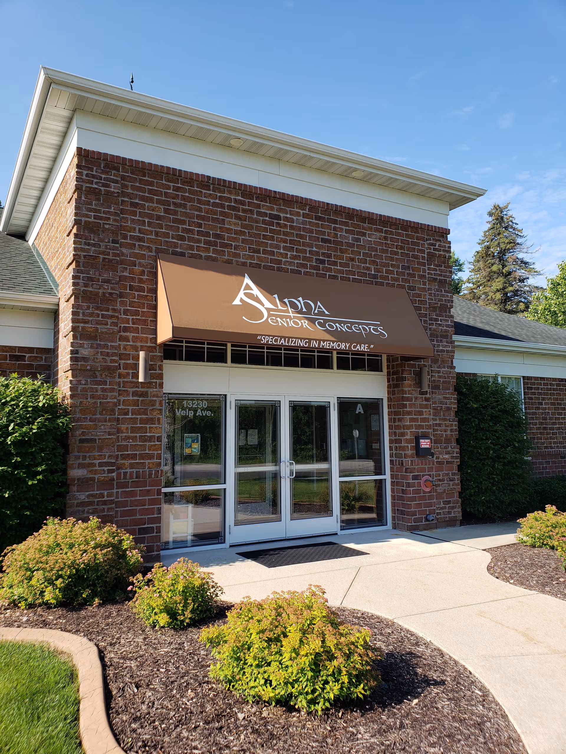 Exterior brick building with Alpha Senior Concepts sign above glass entrance.