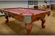 Ornate pool table in a recreation room with seating in a senior facility.
