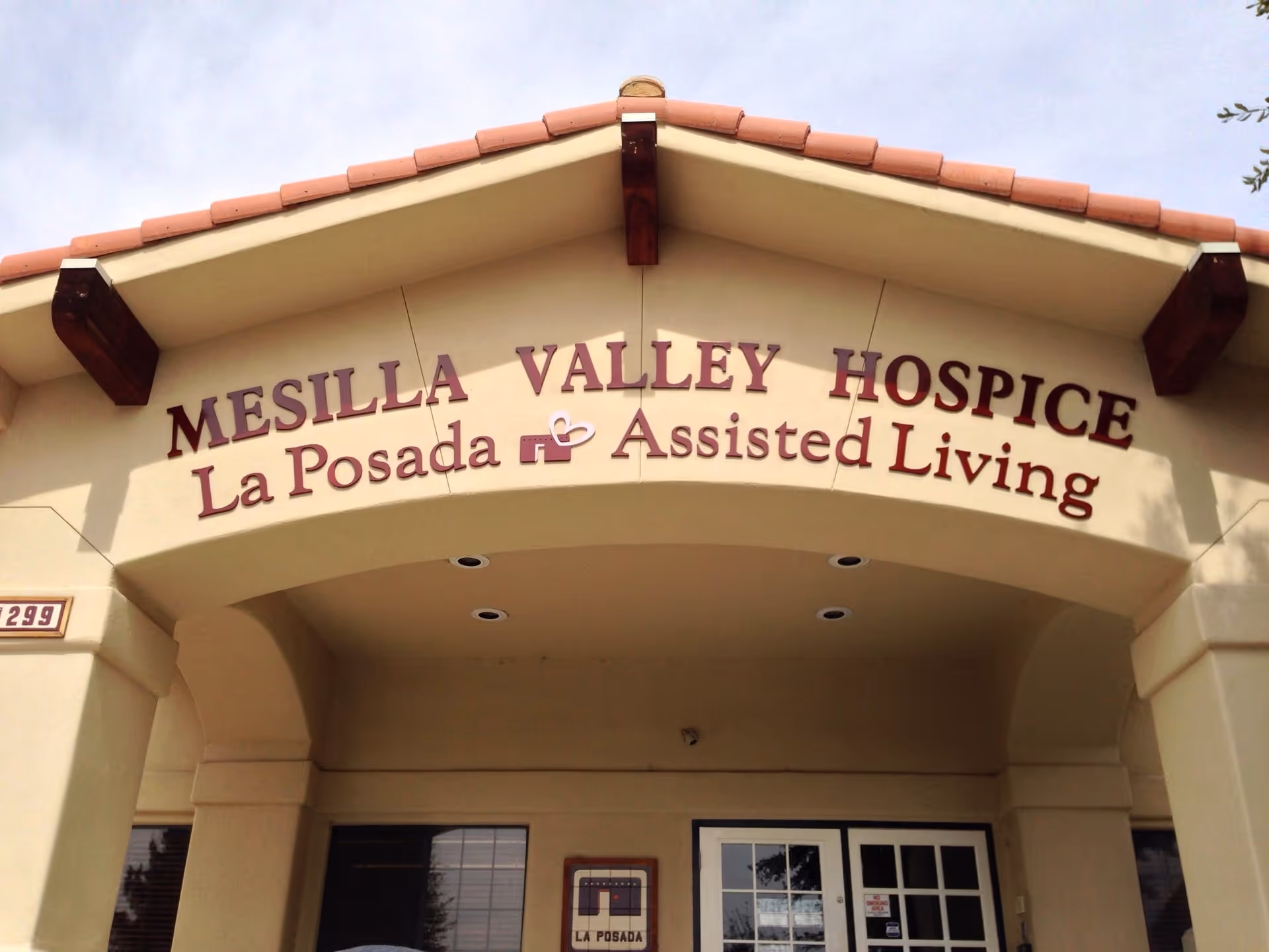 Entrance façade with a sign reading 'Mesilla Valley Hospice La Posada Assisted Living' above an arched portico.