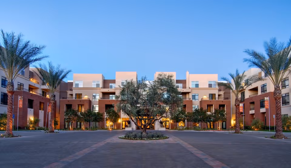 Exterior view of The Village at NorthRidge courtyard with palm trees and building facade.