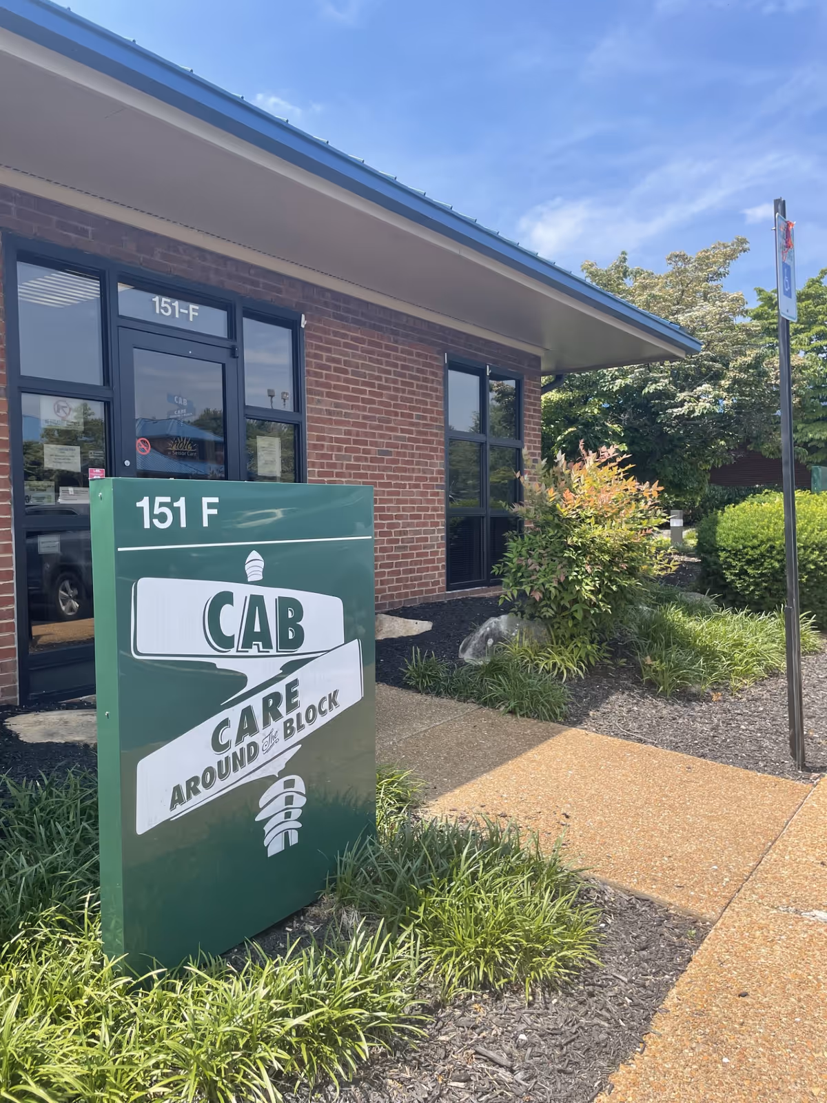 Exterior view of Care Around The Block facility with brick facade, sign, and landscaped walkway.