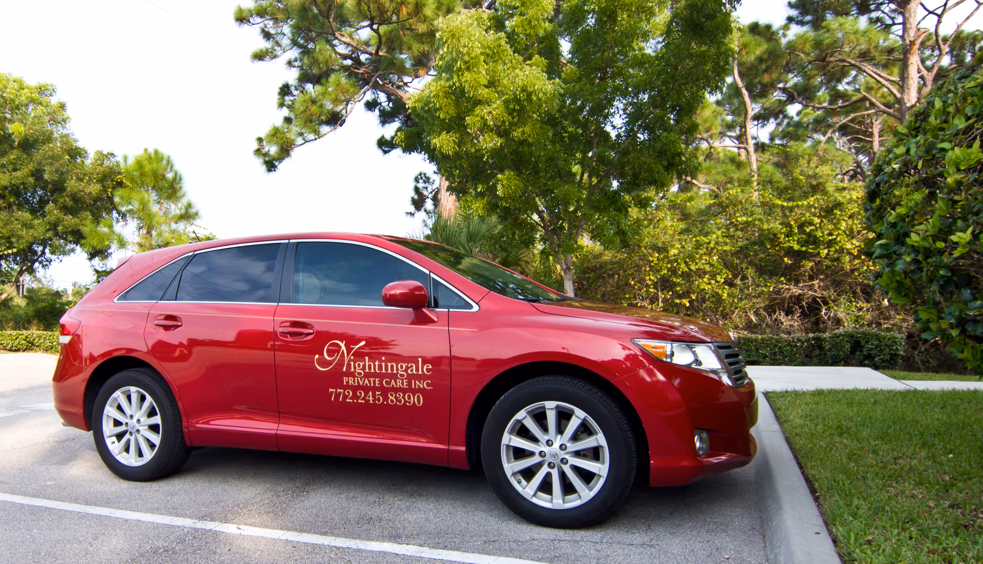 Red branded Nightingale Private Care car parked in a sunny outdoor lot