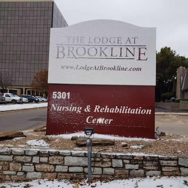 Exterior view of The Lodge at Brookline sign and Nursing & Rehabilitation Center building.