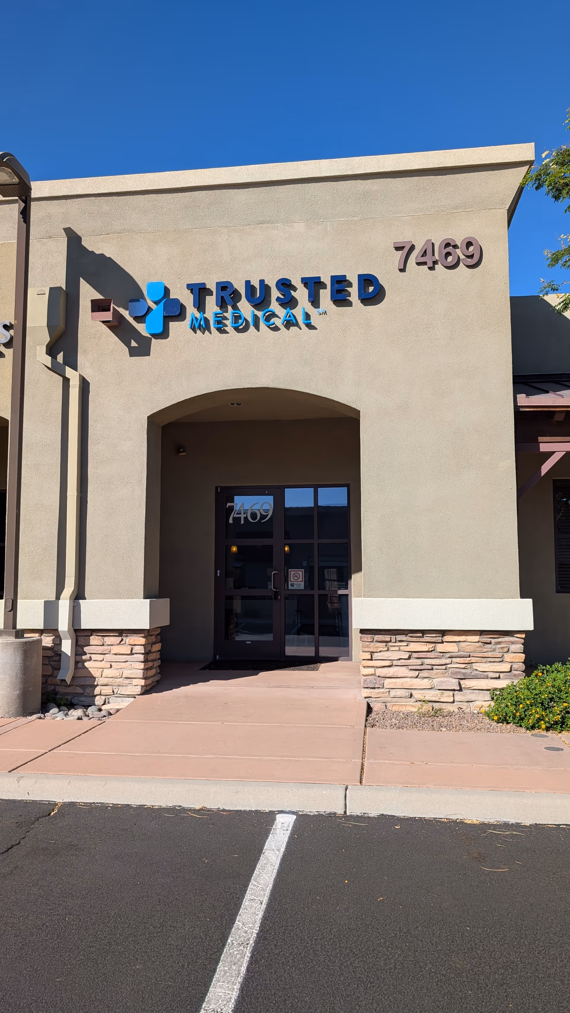 Front exterior of Trusted Medical building with an arched entry and sign.