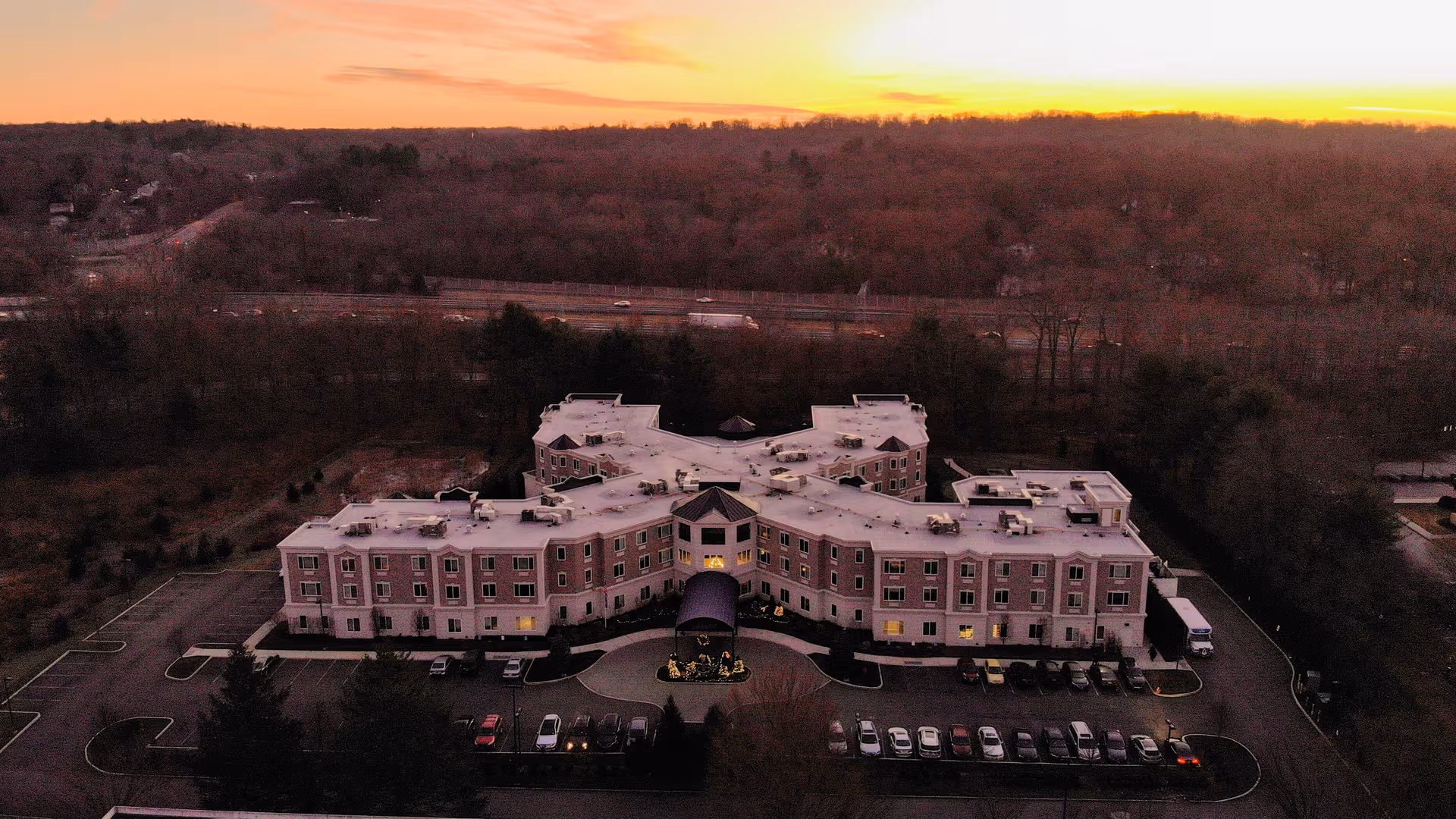 Aerial view of The Bristal Assisted Living at Armonk, pink building complex with parking lot.