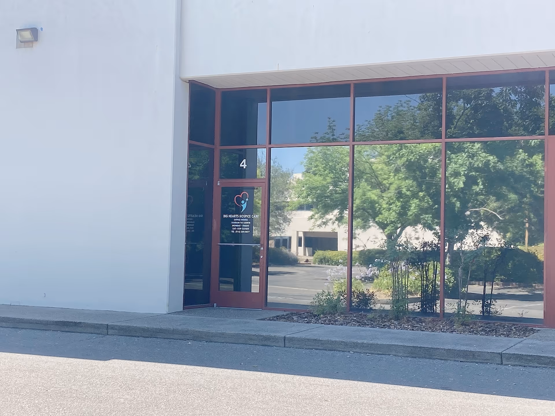 Exterior view of a building entrance with glass windows and a door labeled Big Hearts Hospice.