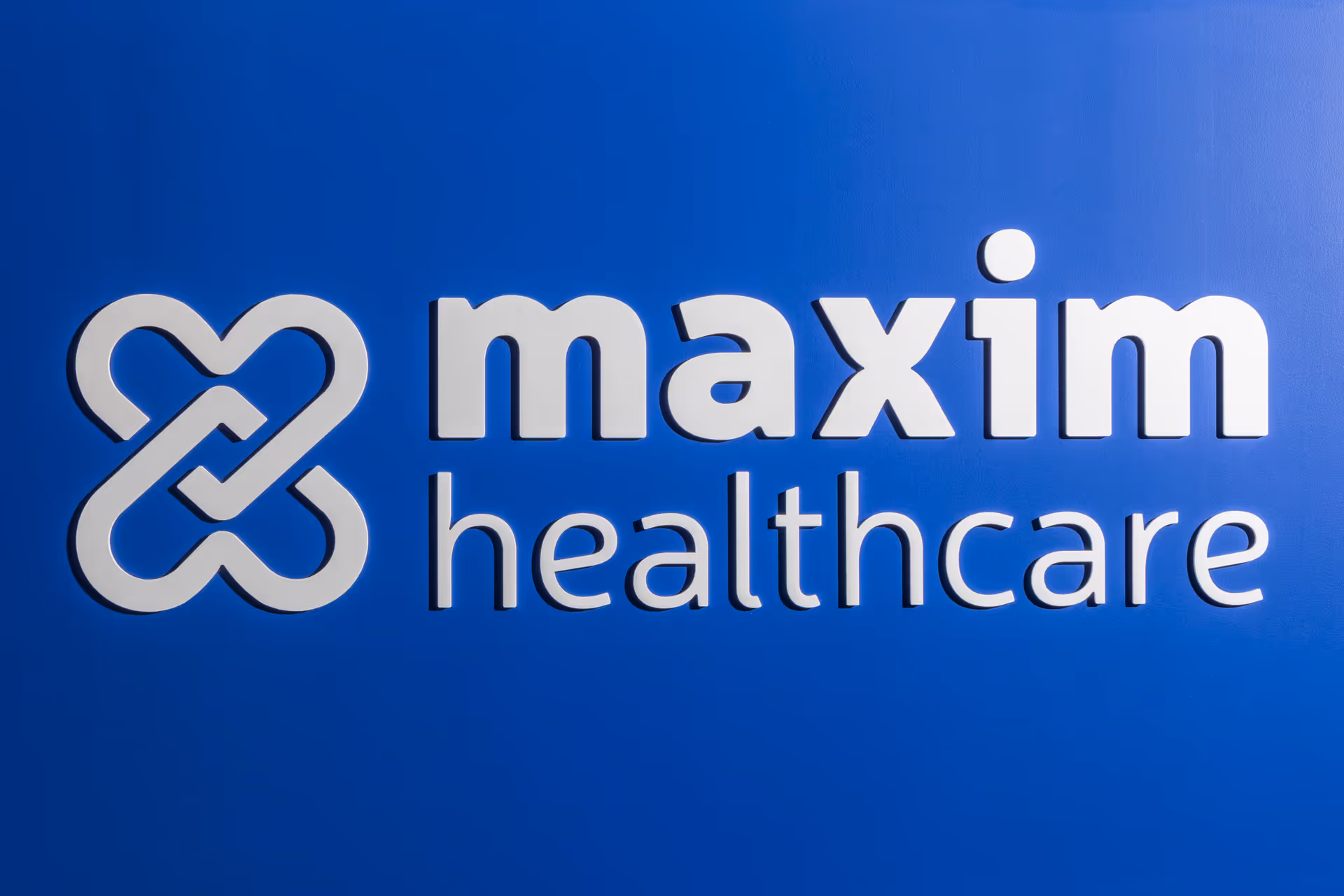 Blue wall with Maxim Healthcare logo and sign.