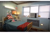 Blue-walled patient bedroom with a bed, window, and decorative accents.