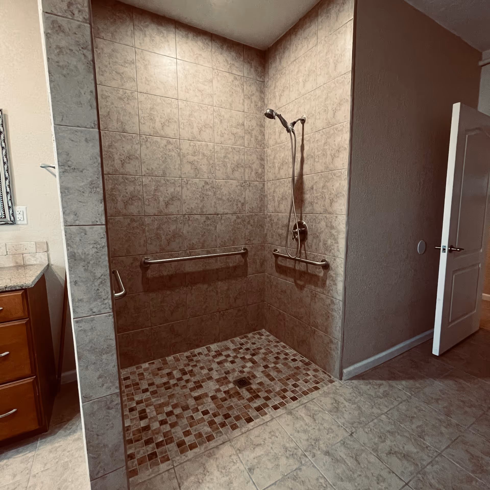 Walk-in bathroom shower with grab bars and tiled walls