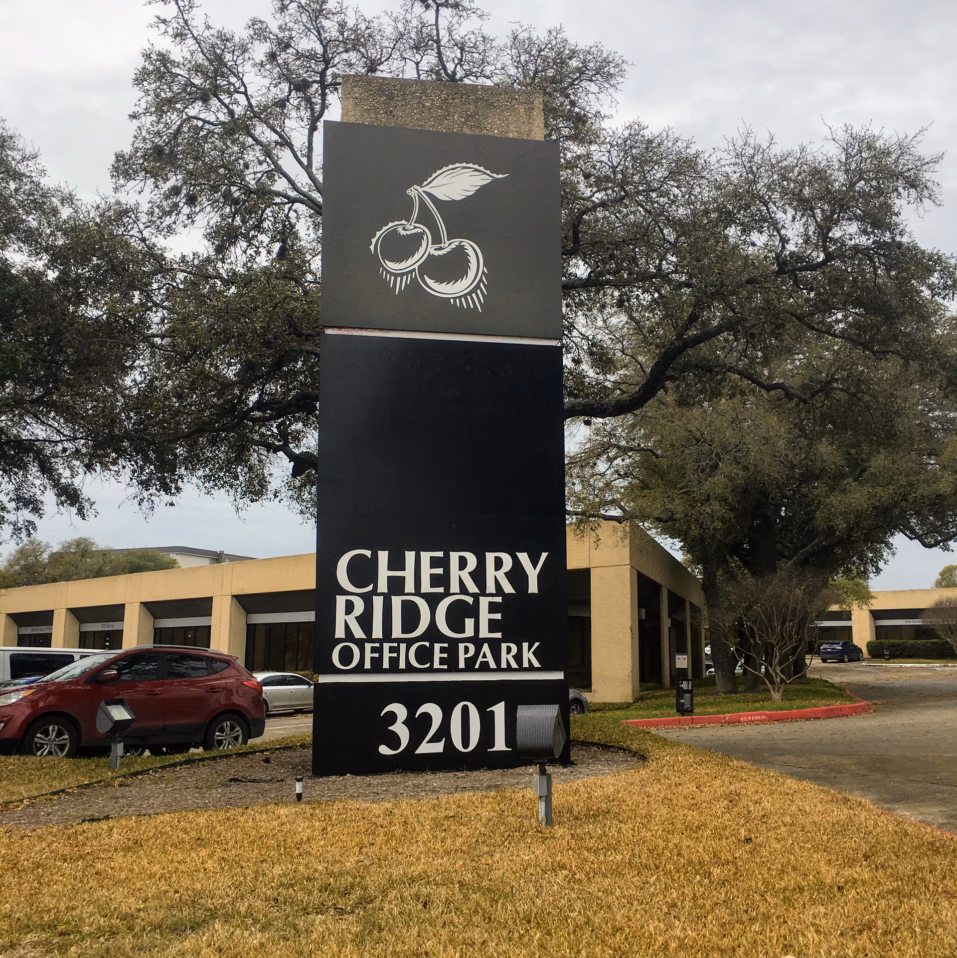 Tall black Cherry Ridge Office Park sign with 3201 in a parking lot.