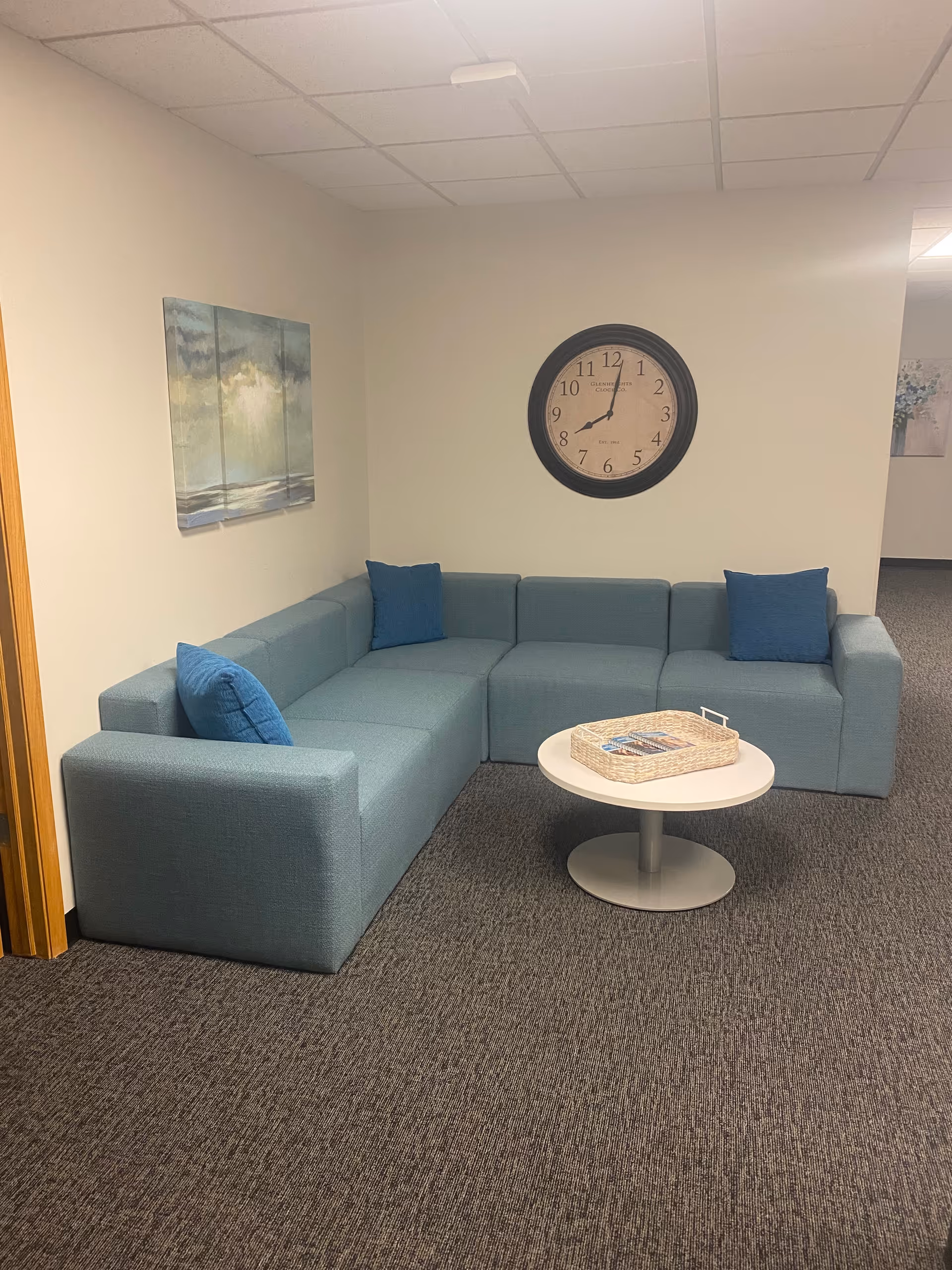 Blue sectional sofa with cushions surrounds a round white coffee table in a lobby seating area.