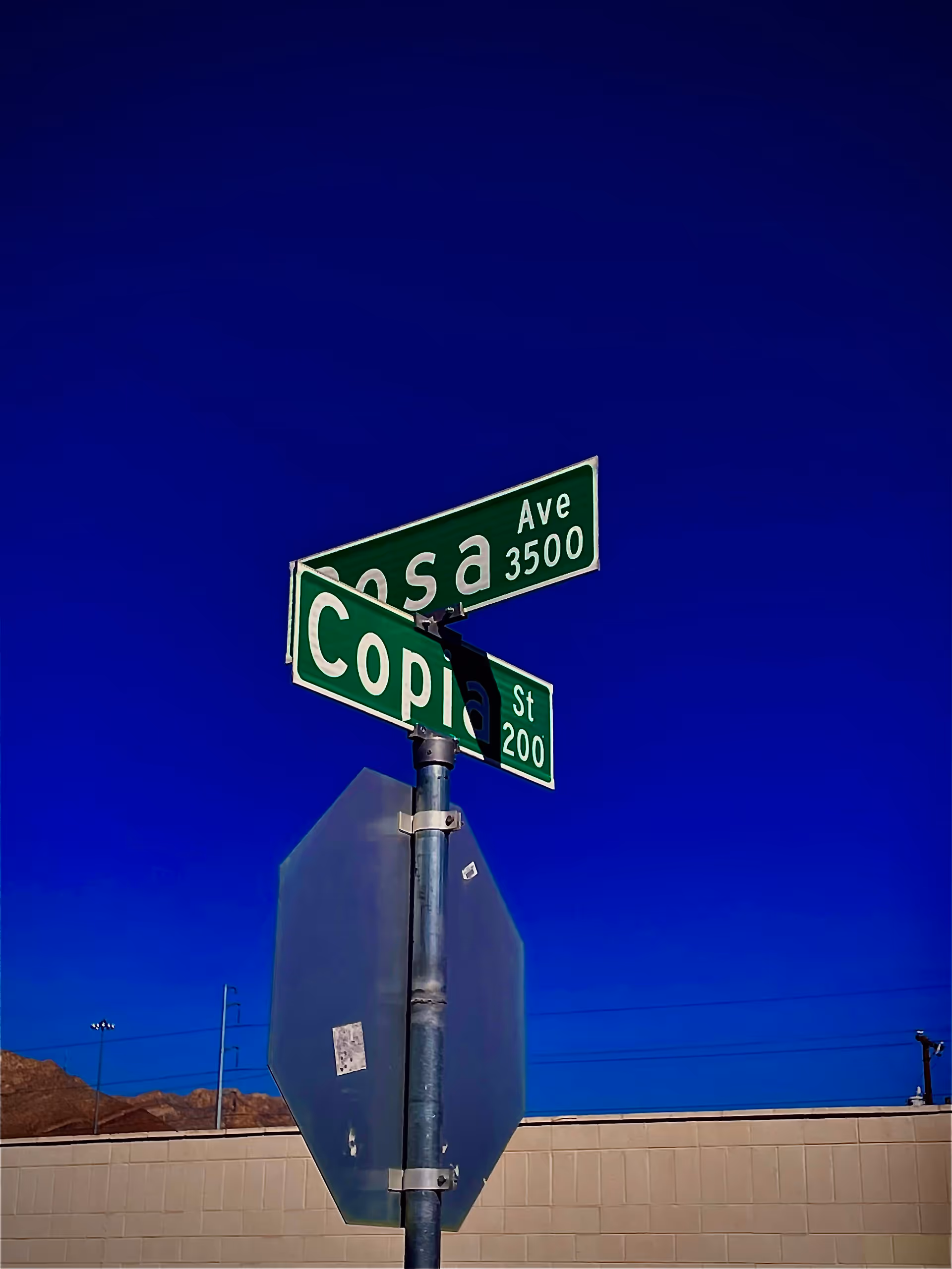 Green street signs on a metal pole against a clear blue sky.